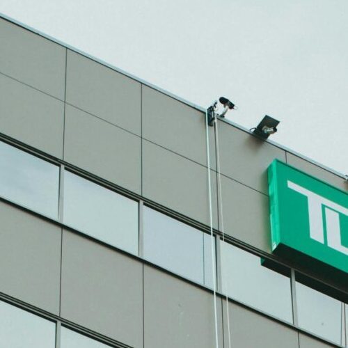 Two professional window cleaners working on a skyscraper with a corporate logo.